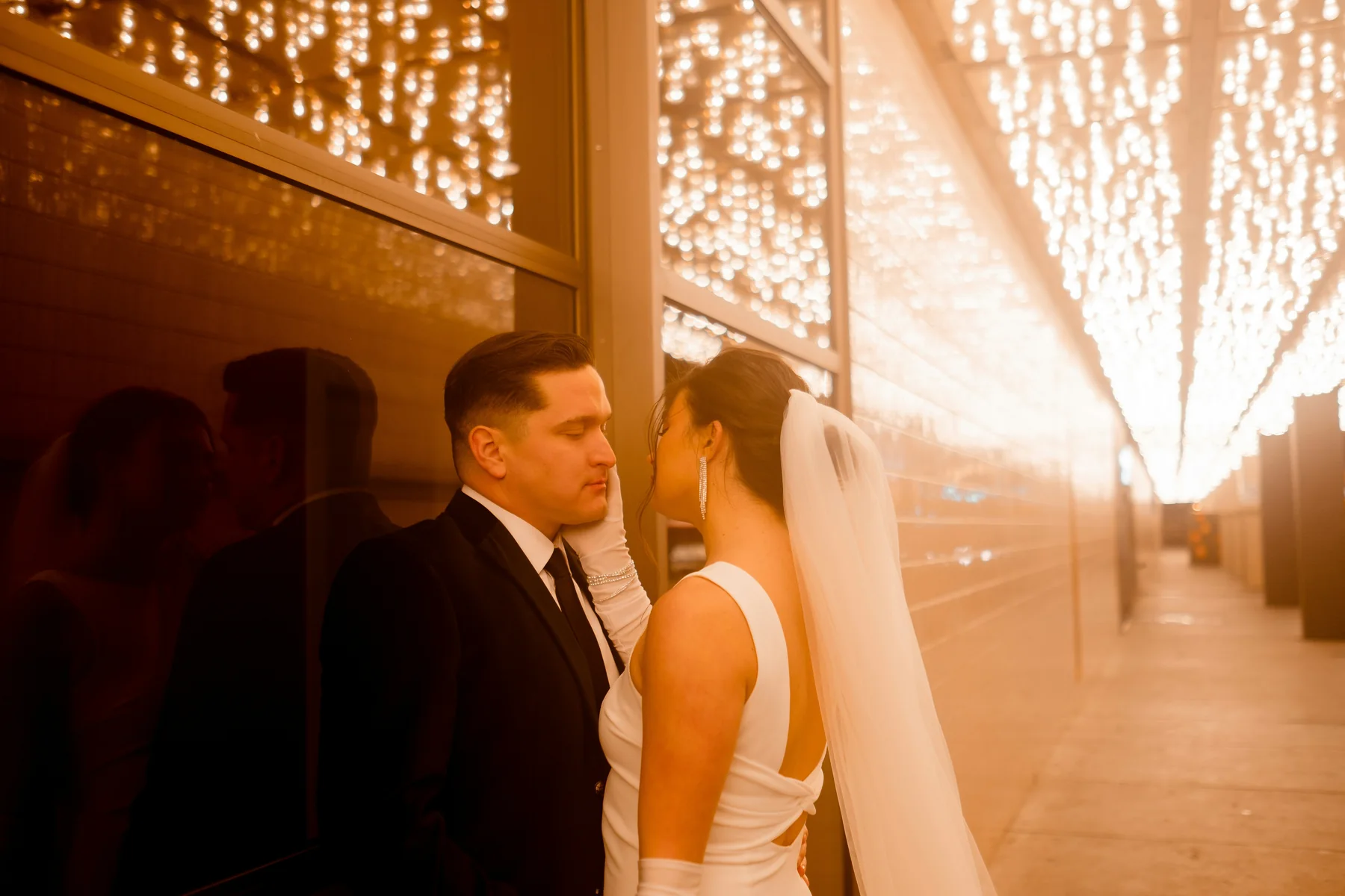 Bride and groom standing beneath warm decorative lights