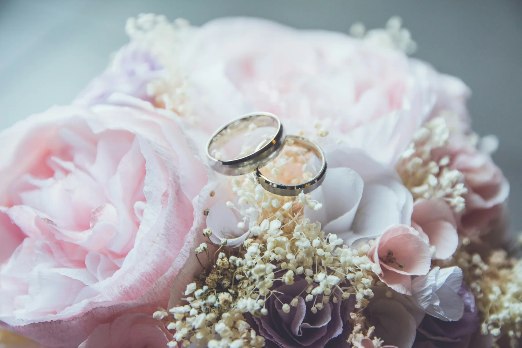 Wedding rings resting on pale flowers